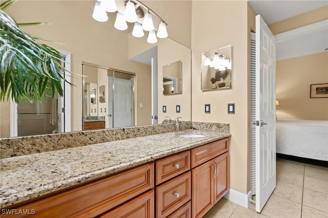 ensuite bathroom with baseboards, connected bathroom, tile patterned flooring, vanity, and a notable chandelier