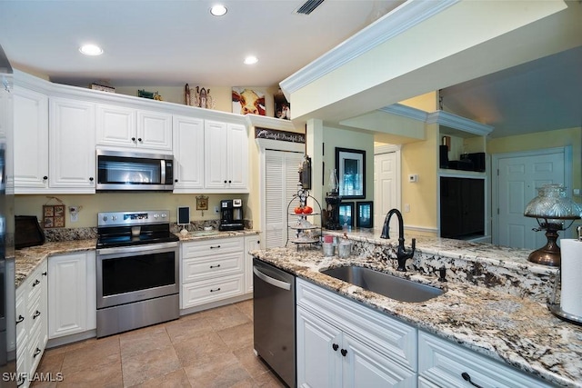 kitchen with visible vents, white cabinets, light stone counters, stainless steel appliances, and a sink