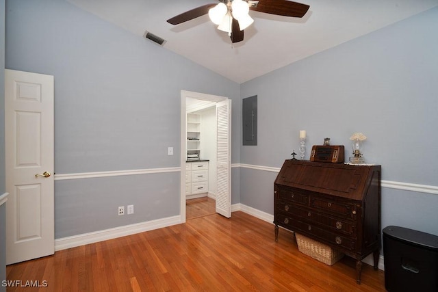 bedroom with wood finished floors, visible vents, baseboards, vaulted ceiling, and electric panel