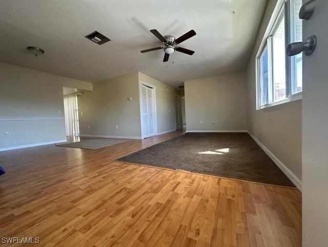 spare room featuring a ceiling fan, visible vents, baseboards, and wood finished floors