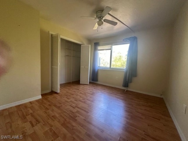 unfurnished bedroom featuring a ceiling fan, a closet, baseboards, and wood finished floors