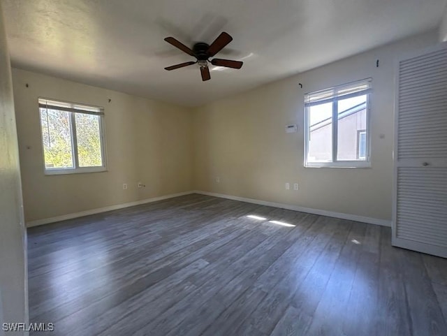 unfurnished room featuring a wealth of natural light, ceiling fan, baseboards, and wood finished floors