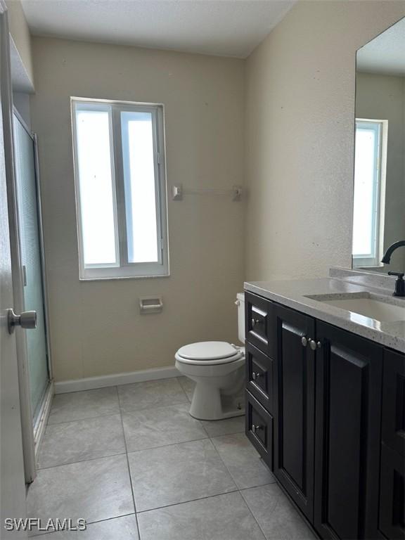 full bathroom featuring toilet, tile patterned flooring, baseboards, and vanity