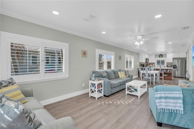 living room with ornamental molding, visible vents, and baseboards