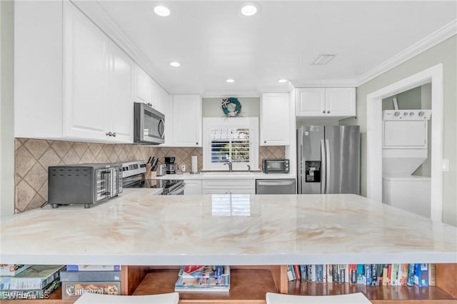 kitchen featuring stainless steel appliances, stacked washer and dryer, visible vents, light stone countertops, and a kitchen bar