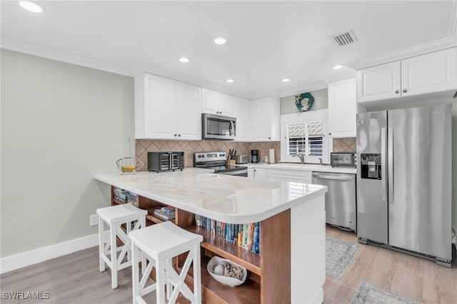 kitchen with tasteful backsplash, visible vents, appliances with stainless steel finishes, a peninsula, and light countertops