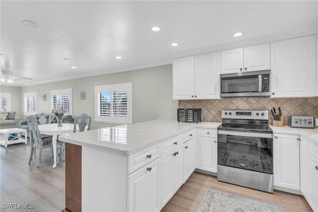 kitchen with a peninsula, plenty of natural light, appliances with stainless steel finishes, and light countertops