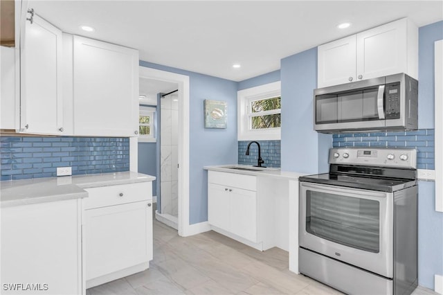 kitchen featuring white cabinetry, stainless steel appliances, a sink, and light countertops