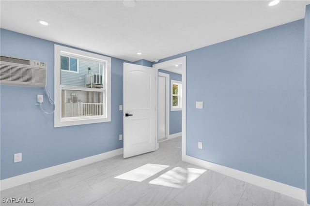 unfurnished room featuring a wall unit AC, baseboards, and recessed lighting