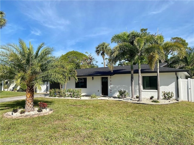 view of front of house with fence, a front lawn, and stucco siding