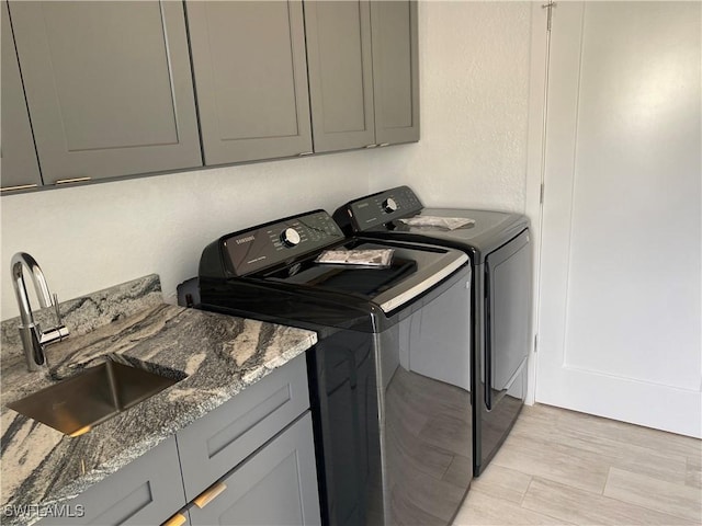 81 Cardinal Dr, North Fort Myers, FL 33917 - washroom featuring a textured wall, separate washer and dryer, a sink, light wood-style floors, and cabinet space