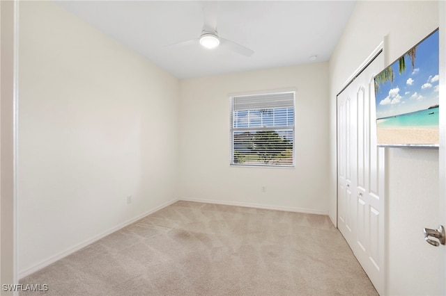 spare room featuring light carpet, ceiling fan, and baseboards