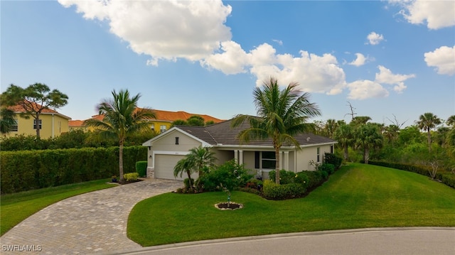 view of front of house with decorative driveway, a tile roof, stucco siding, a front yard, and a garage