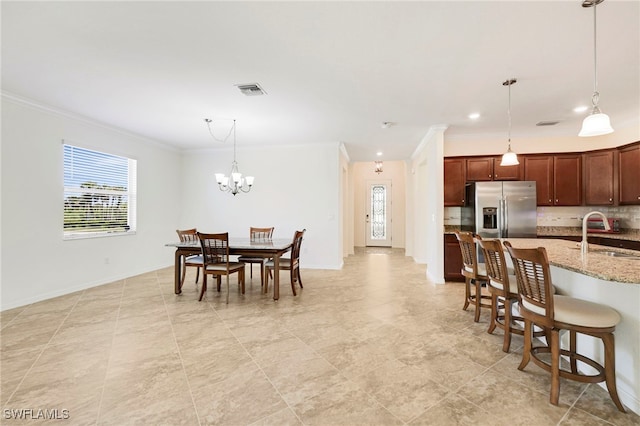 dining space with baseboards, ornamental molding, visible vents, and a notable chandelier