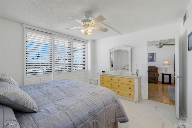 bedroom featuring marble finish floor, a ceiling fan, visible vents, and a textured ceiling