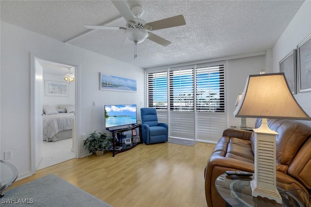 living room with a textured ceiling, light wood finished floors, and a ceiling fan