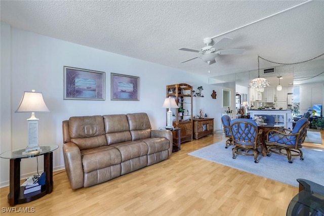 living room with light wood-style floors, visible vents, ceiling fan, and a textured ceiling