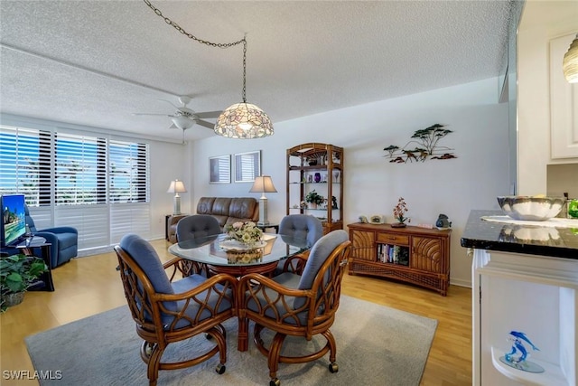 dining room featuring baseboards, light wood-style flooring, and a textured ceiling