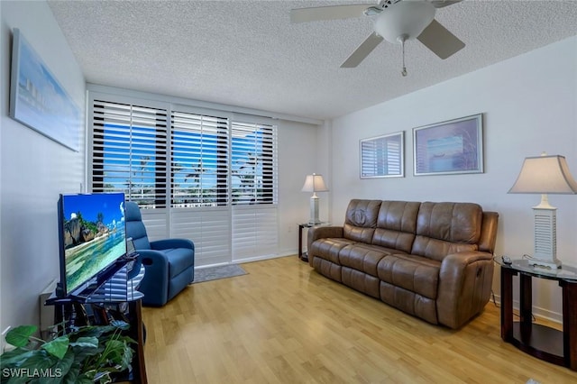 living room with a textured ceiling, a ceiling fan, and wood finished floors