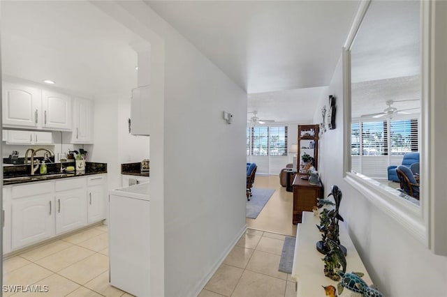 hallway featuring washer / clothes dryer, a sink, baseboards, and light tile patterned floors