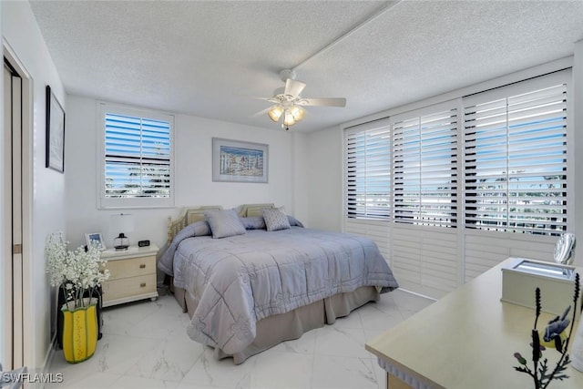 bedroom featuring marble finish floor, ceiling fan, and a textured ceiling