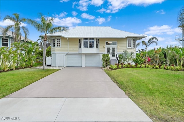 view of front of home featuring a front yard, metal roof, driveway, and an attached garage