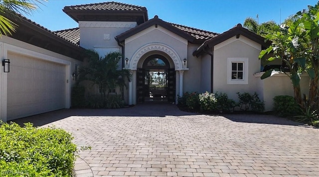 entrance to property featuring stucco siding, a tile roof, and decorative driveway