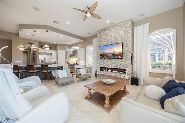 living room featuring visible vents, recessed lighting, a fireplace, arched walkways, and a ceiling fan