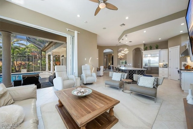 living area featuring light tile patterned floors, visible vents, arched walkways, and ceiling fan