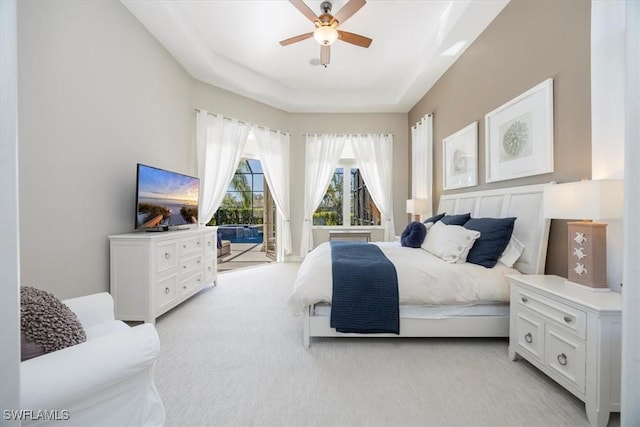 bedroom featuring light carpet, a raised ceiling, ceiling fan, and access to outside