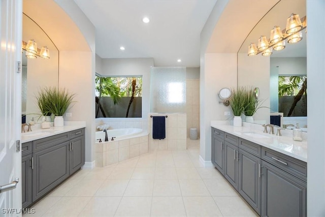 bathroom with tile patterned flooring, a bath, two vanities, and a sink