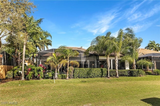 rear view of property with a lanai, stucco siding, and a yard