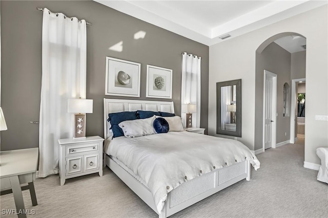 carpeted bedroom with arched walkways, visible vents, and baseboards