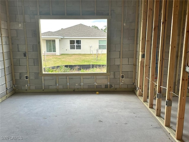 empty room with concrete flooring, concrete block wall, and a healthy amount of sunlight