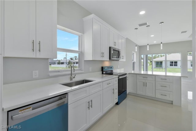 13224 Foresman Blvd, Port Charlotte, FL 33981 - kitchen featuring appliances with stainless steel finishes, a peninsula, plenty of natural light, white cabinets, and recessed lighting