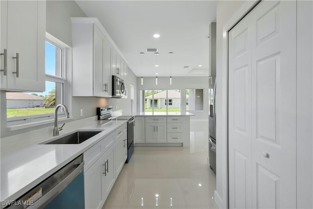 13224 Foresman Blvd, Port Charlotte, FL 33981 - kitchen featuring stainless steel appliances, a peninsula, white cabinets, light countertops, and pendant lighting