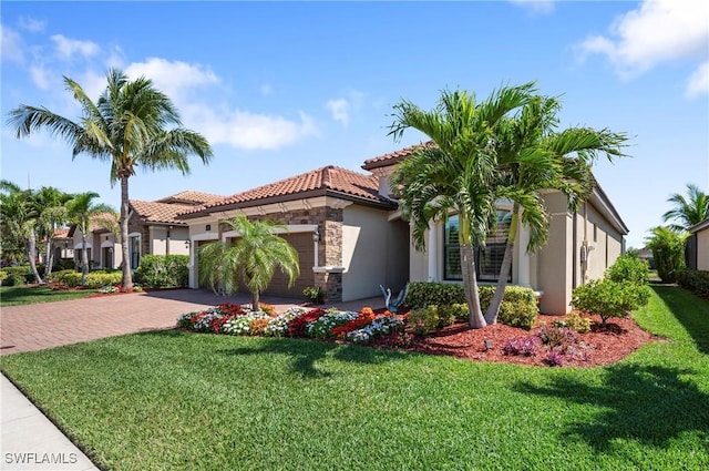 mediterranean / spanish-style house with decorative driveway, a front yard, a garage, stone siding, and a tiled roof