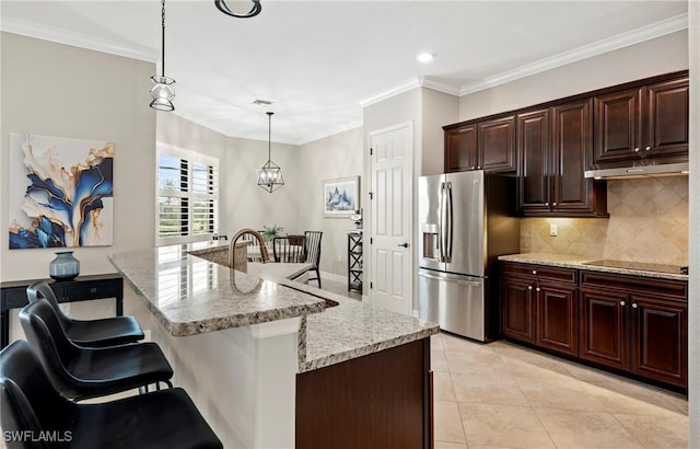 kitchen with light tile patterned flooring, black electric cooktop, under cabinet range hood, ornamental molding, and stainless steel fridge