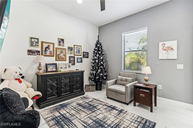 living area with marble finish floor, ceiling fan, and baseboards