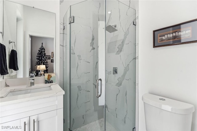 bathroom with toilet, a marble finish shower, and vanity