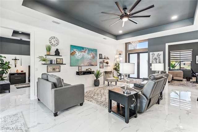 living area with a tray ceiling, marble finish floor, visible vents, and french doors