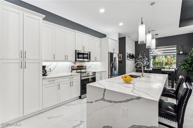 kitchen with marble finish floor, stainless steel appliances, decorative backsplash, a kitchen island with sink, and a sink