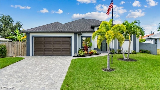 view of front of house with a front yard, decorative driveway, fence, and an attached garage