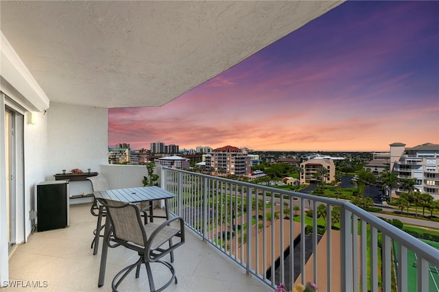 balcony at dusk featuring a view of city