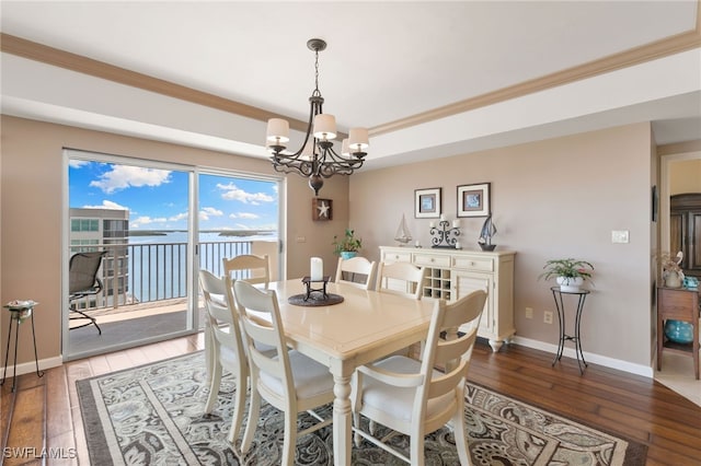 dining room with a tray ceiling, hardwood / wood-style floors, crown molding, baseboards, and a chandelier