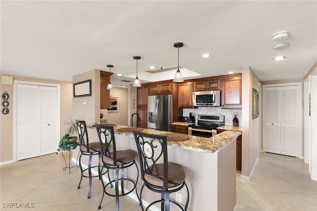 kitchen with a breakfast bar, backsplash, a peninsula, and stainless steel appliances