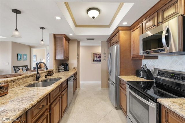 kitchen with backsplash, a tray ceiling, brown cabinetry, stainless steel appliances, and a sink