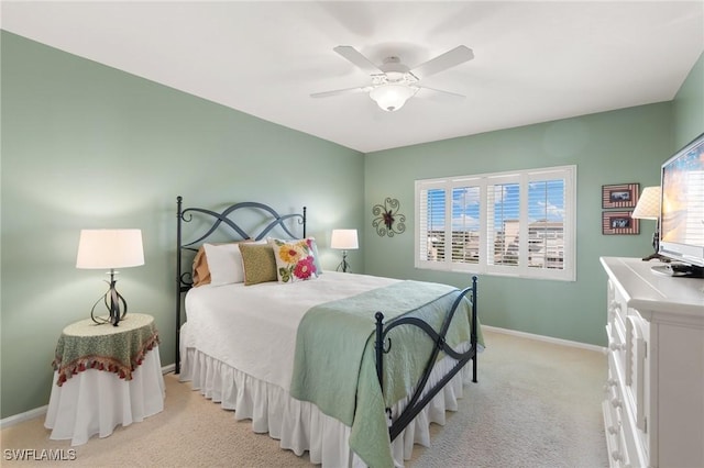 bedroom with a ceiling fan, baseboards, and light carpet