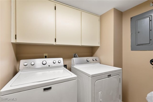 washroom with electric panel, cabinet space, and washer and clothes dryer