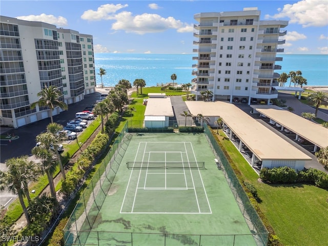 view of tennis court with fence and a water view